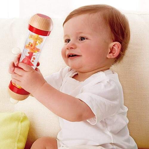 Bebe de 7 meses sentado con el palo de lluvia, juegos y juguetes para bebés desde 7 meses